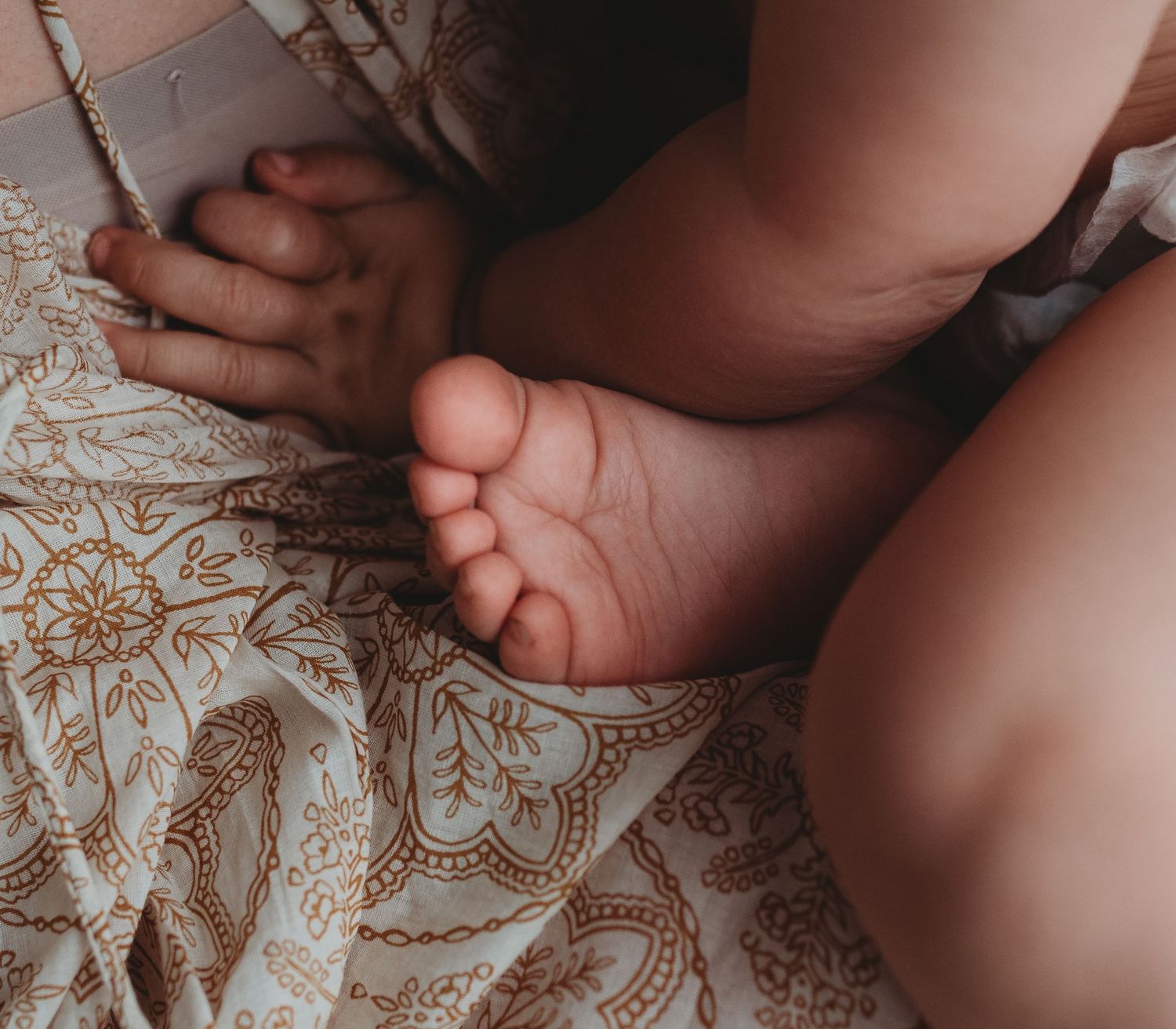 Close-up detail of tiny feet resting on patterned bedding during an intimate photo session.