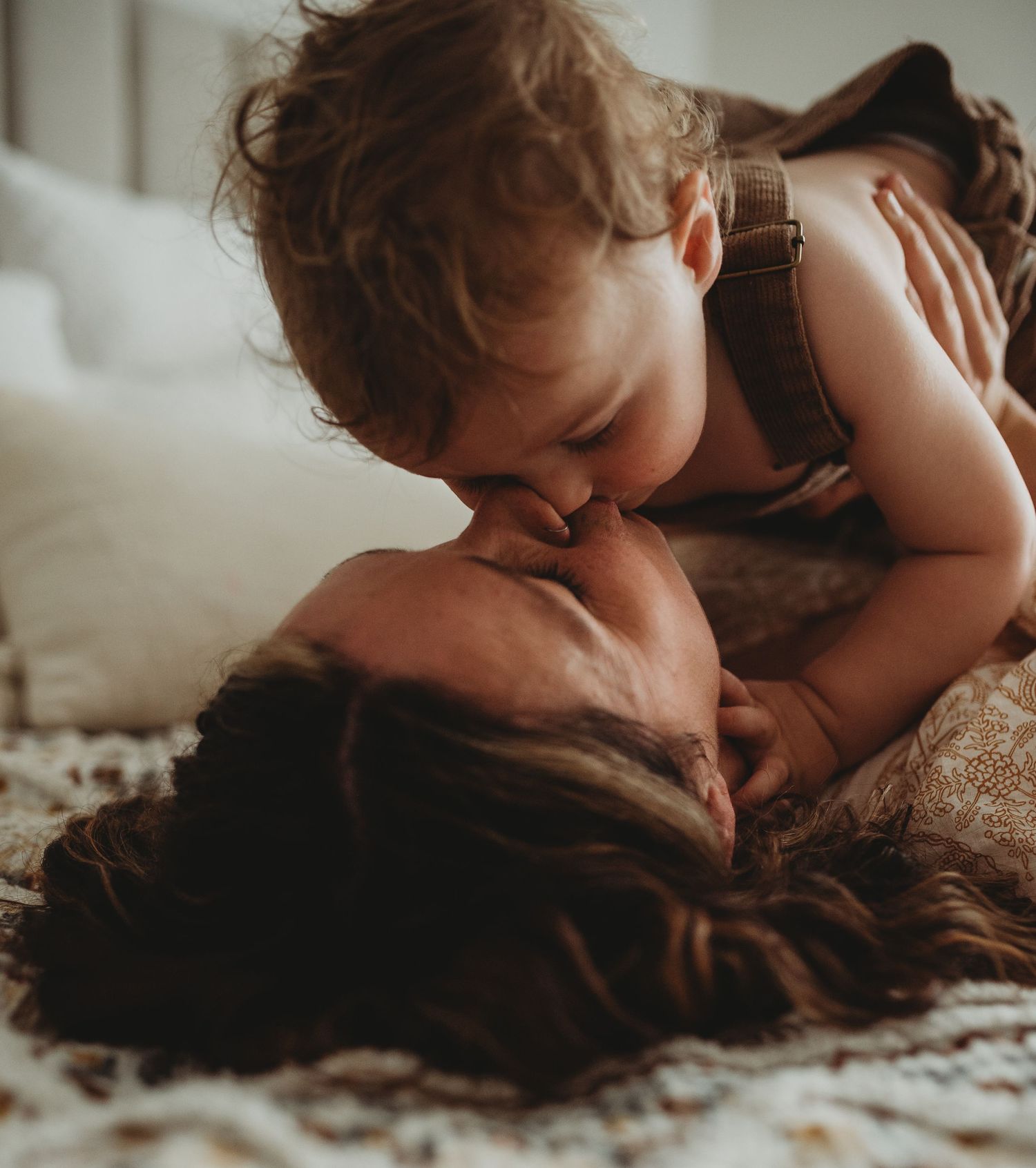 Intimate lifestyle photography with soft shadows and warm tones on textured bedding.