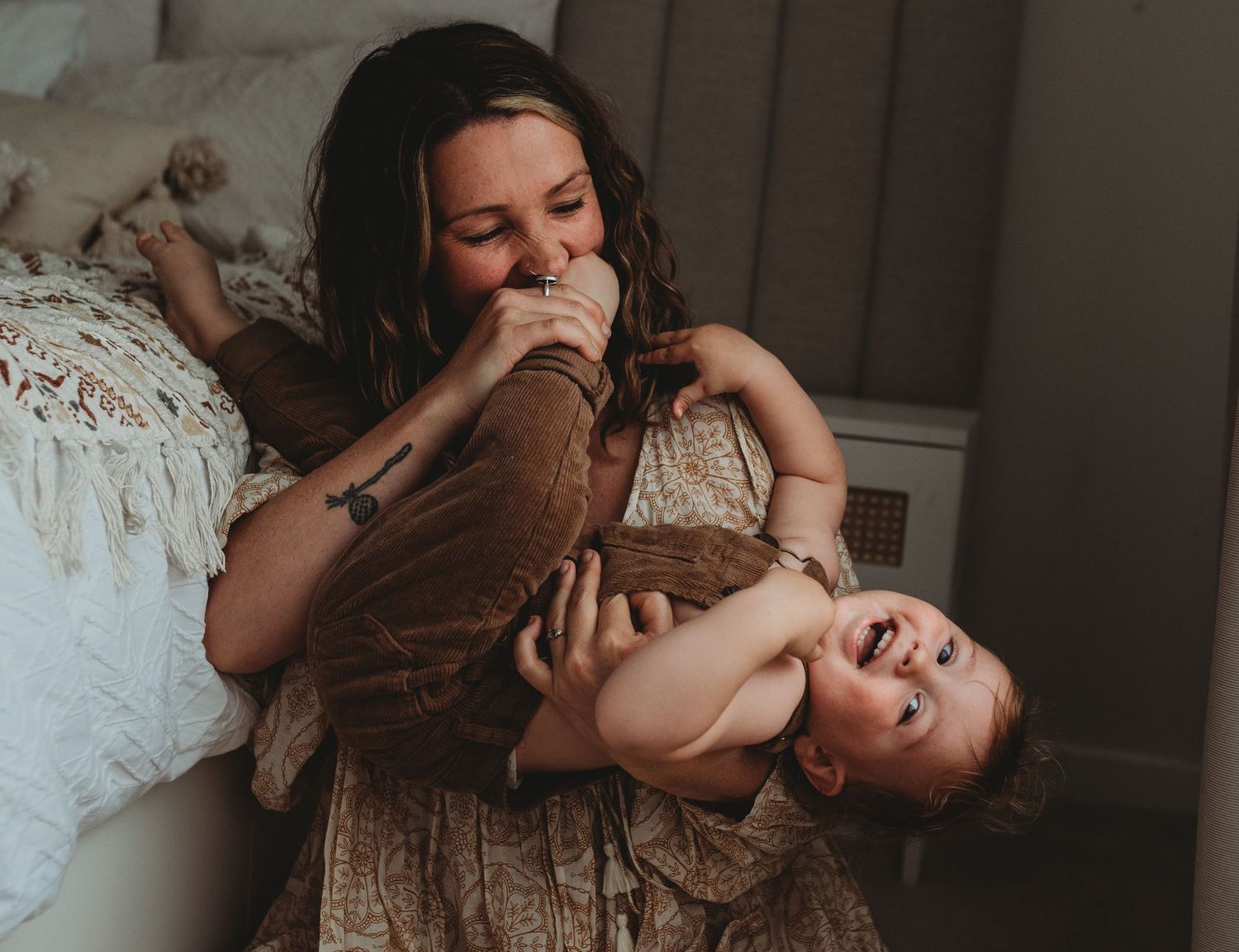 A playful moment of laughter and joy shared between parent and child on a cozy bed.
