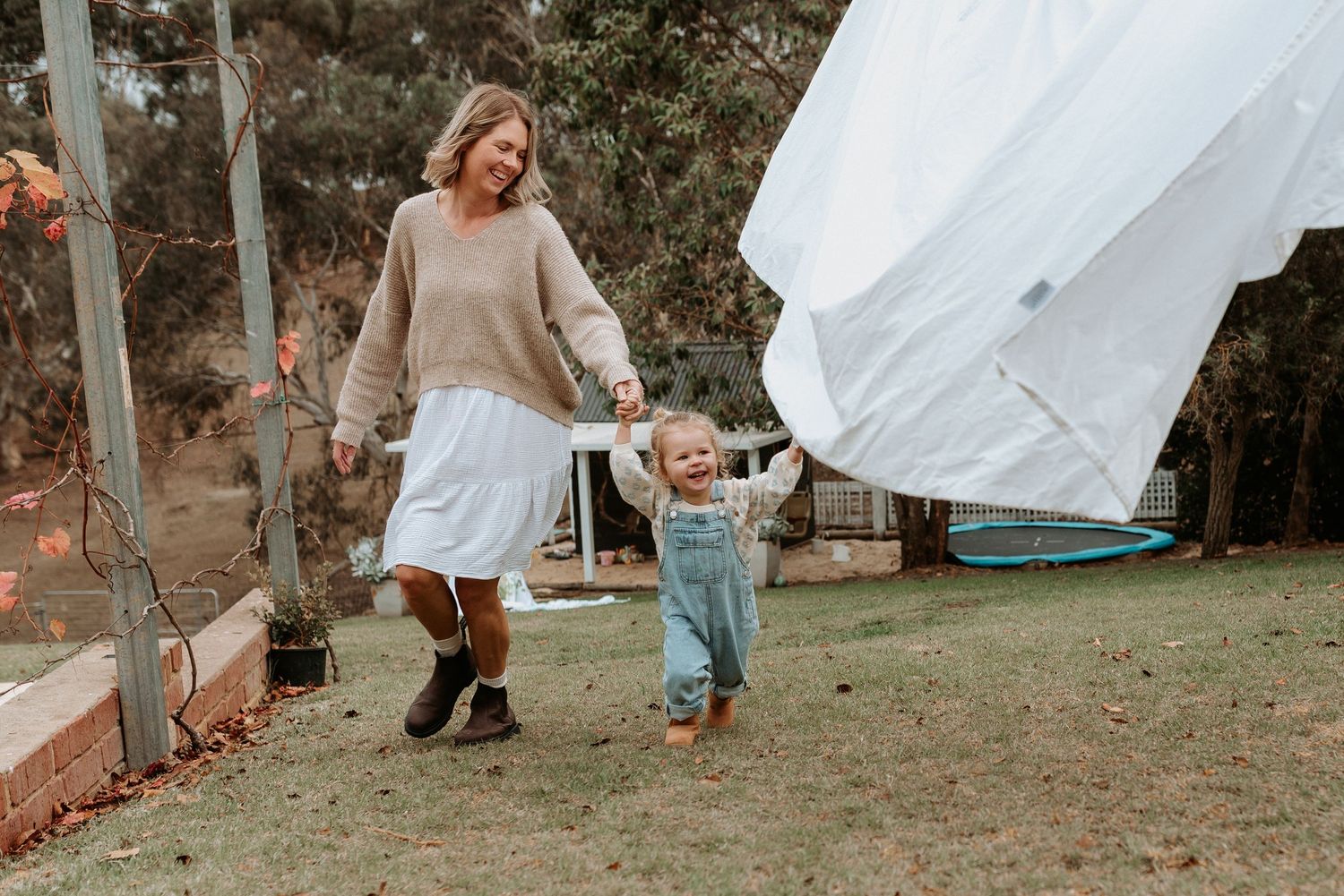 White sheets hanging on a clothesline outdoors create a dreamy backdrop for a playful scene.