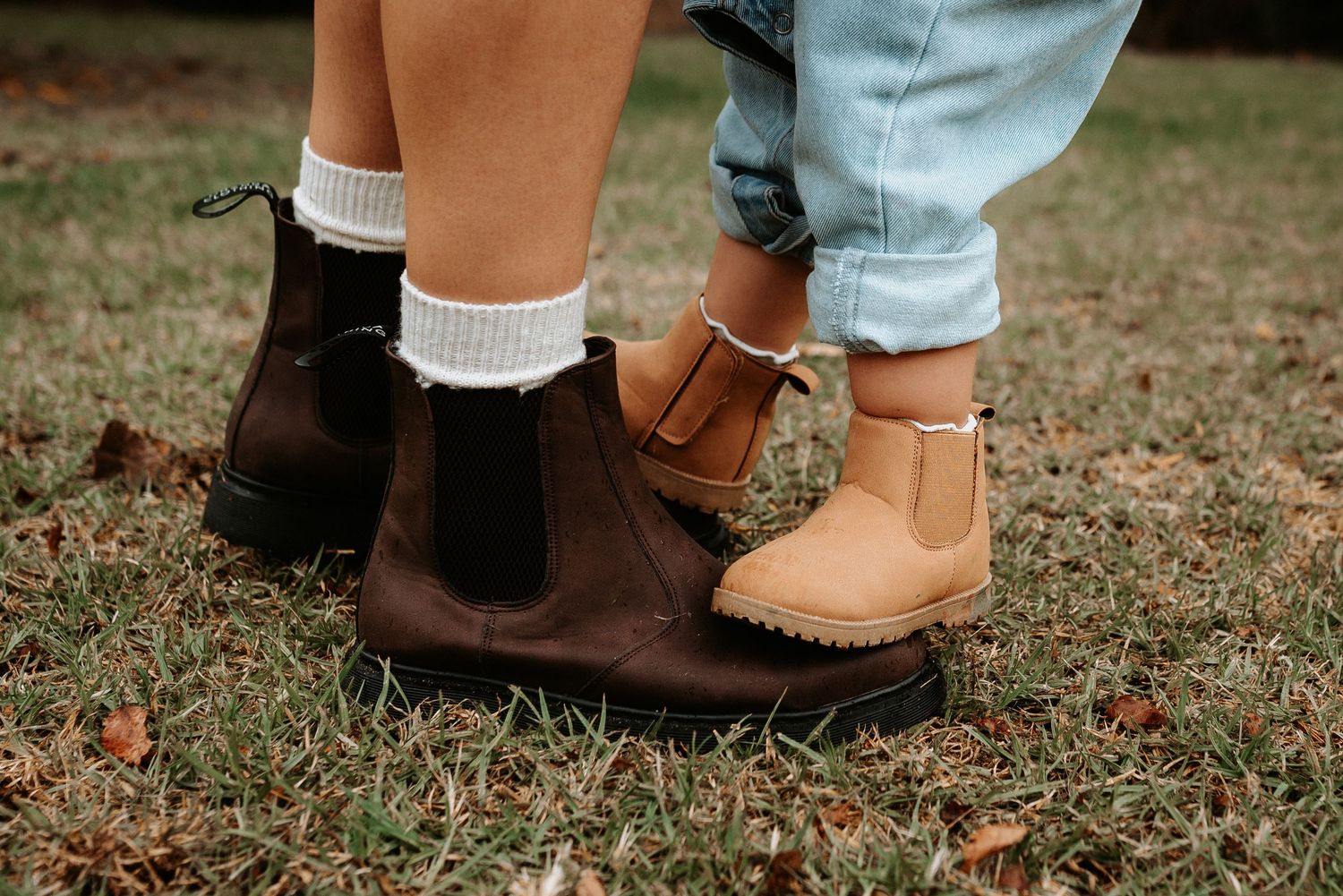 Close-up of various shoes and feet standing together on grass.