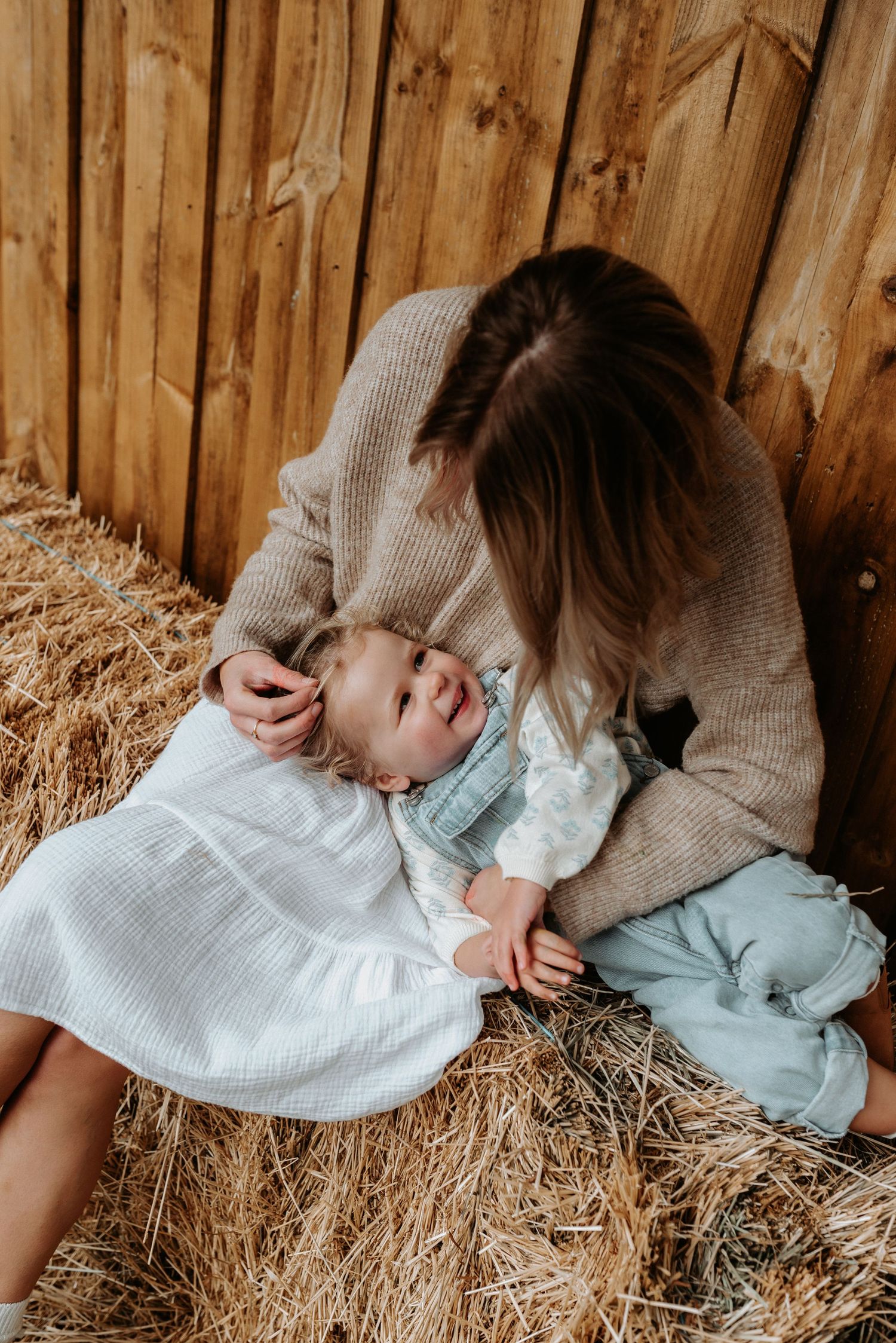Candid moment captured on hay bales showing soft natural lighting and neutral tones.