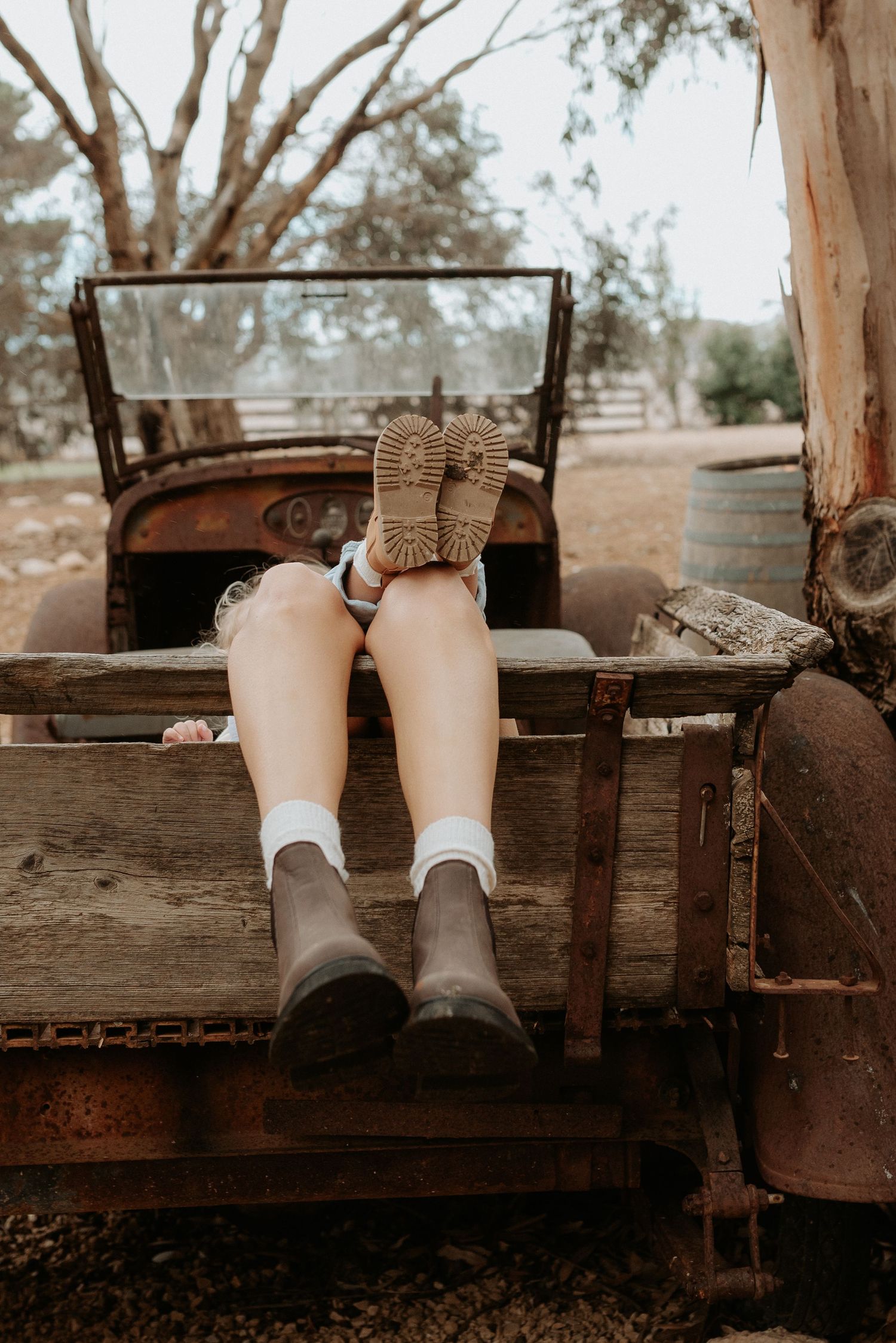 Feet with white socks resting on an old wooden bench in a natural setting.