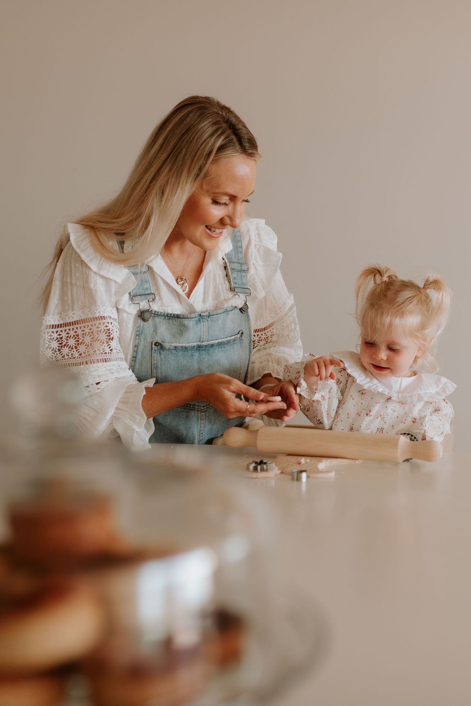 Parent and child baking together in a modern kitchen, wearing matching white tops and denim.