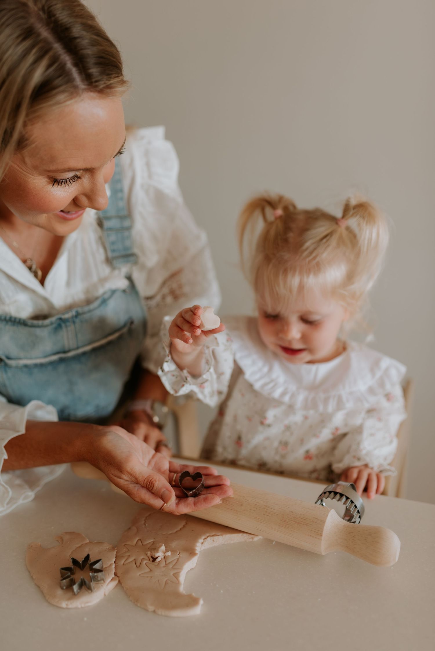 A heartwarming baking scene with cookie cutters and dough on a white counter.