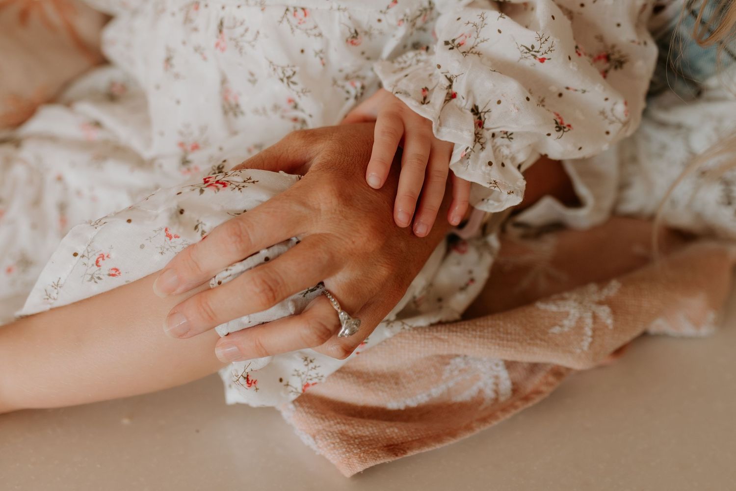 Close-up view of hands resting on a light colored surface.
