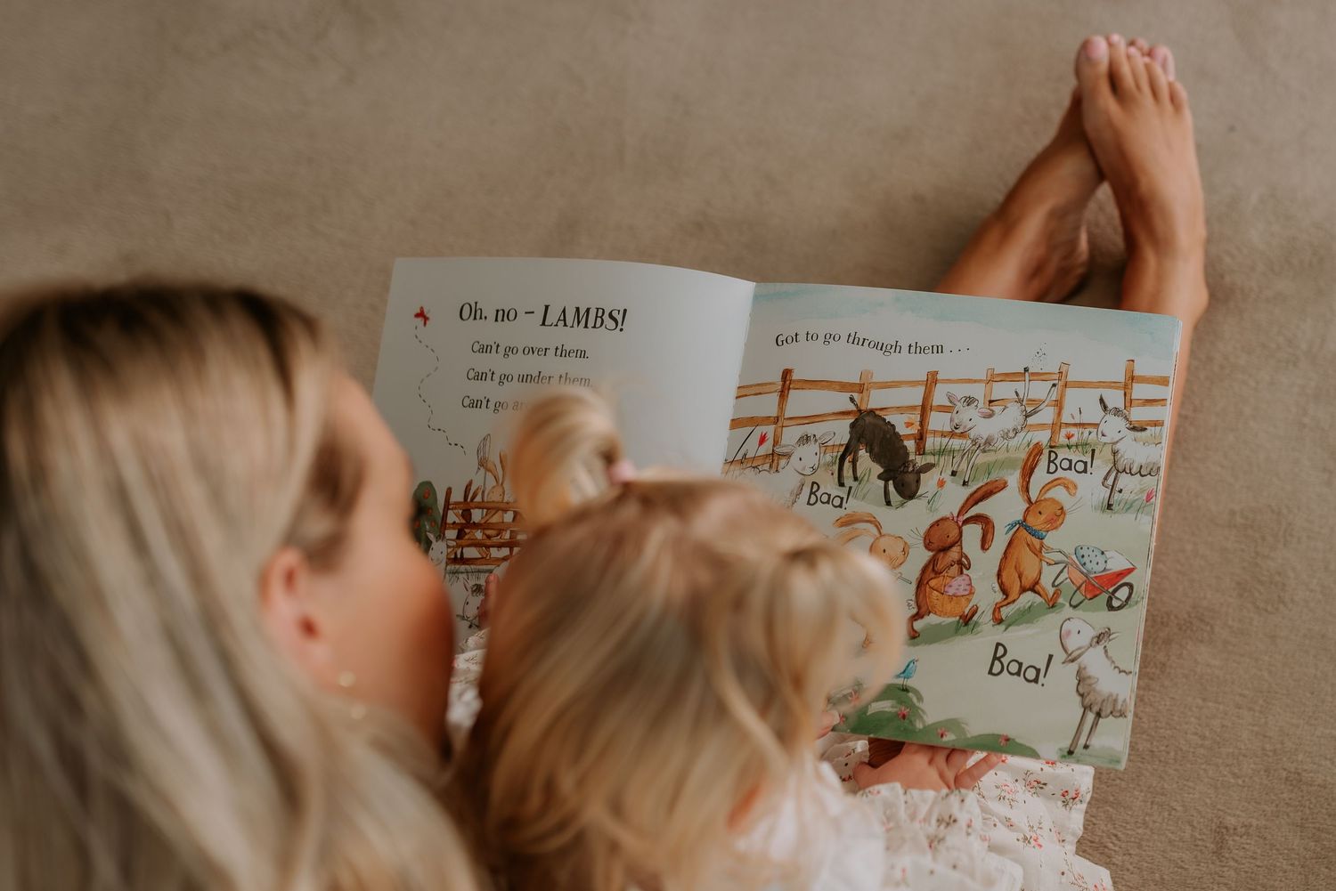 A parent and child reading a picture book together on a couch.