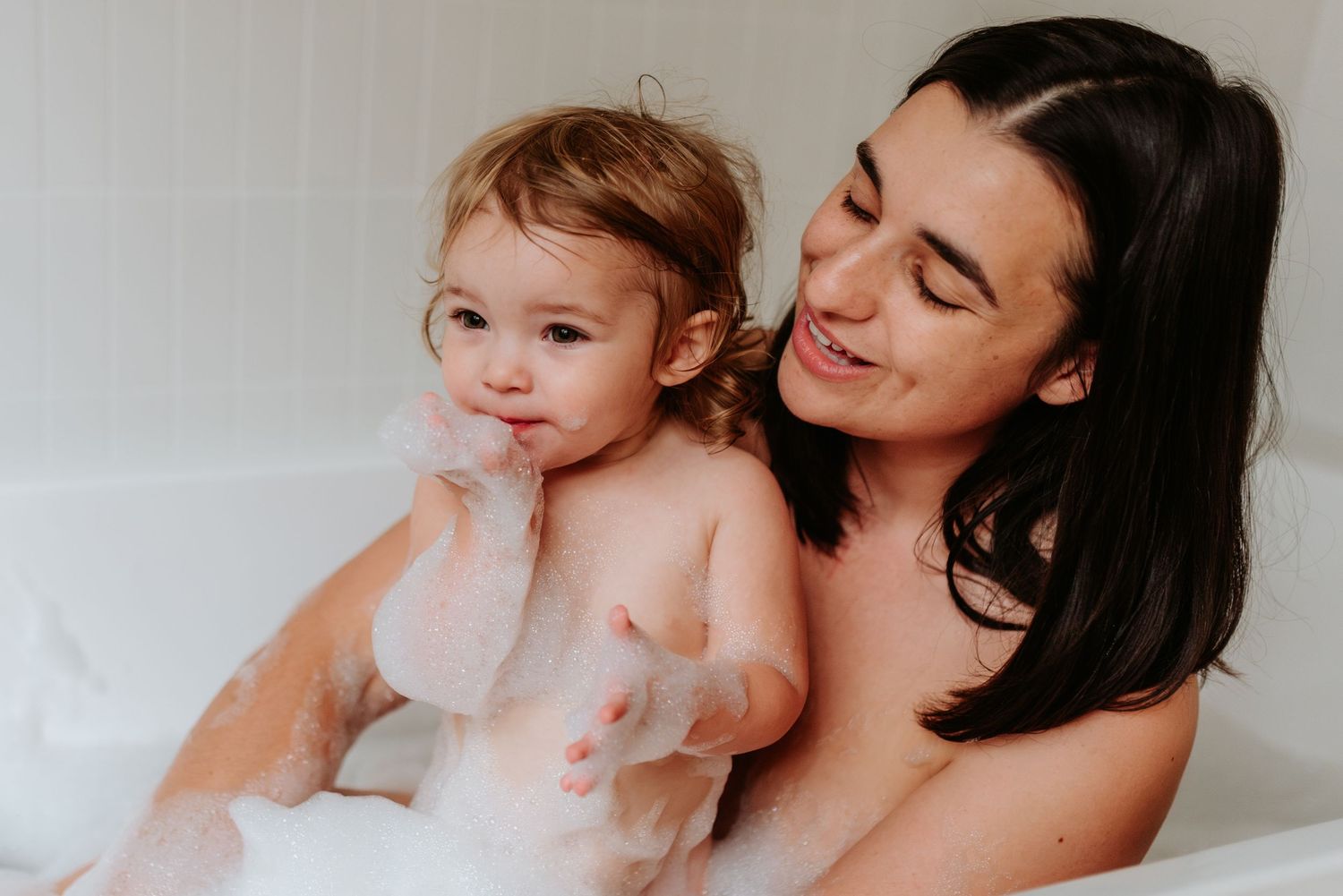 Gentle bath time moment captured in soft lighting with parent and child.