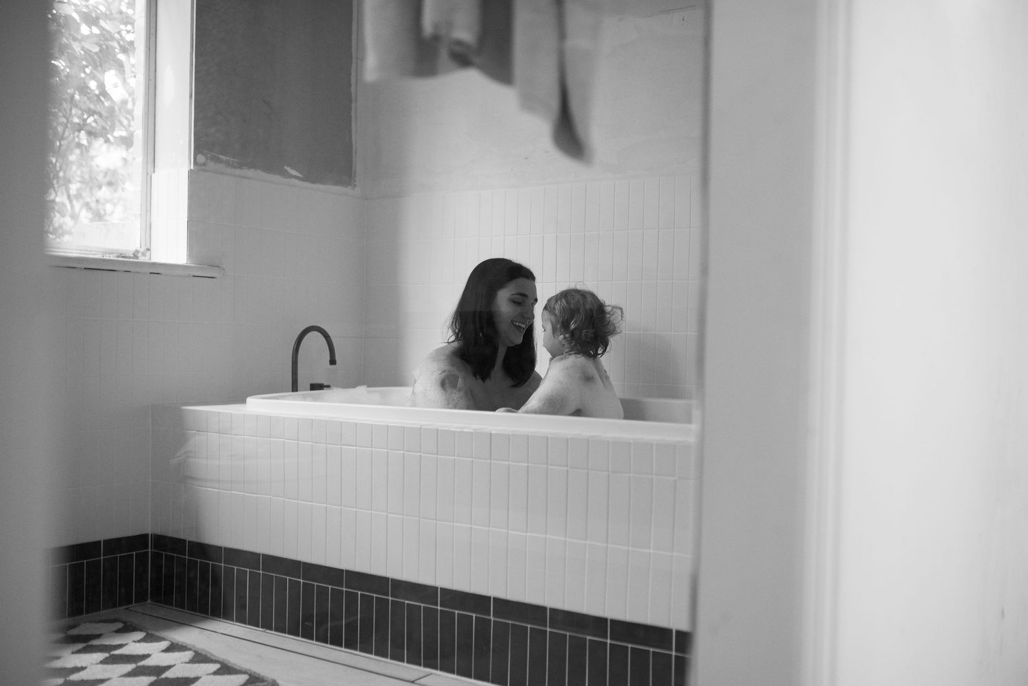 Minimalist bathroom setting with parent and child sharing peaceful bath time.