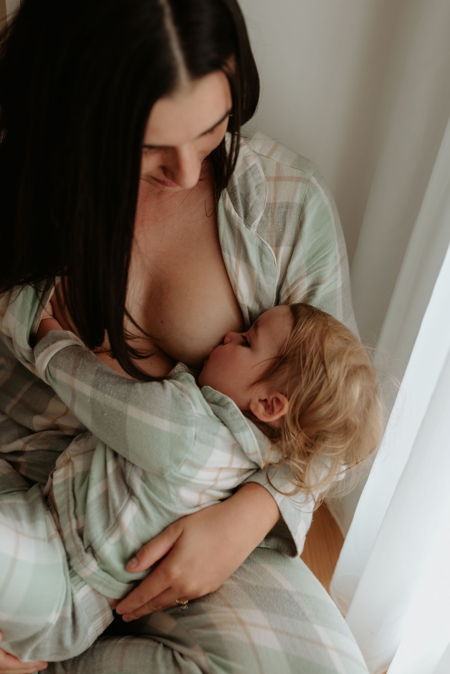 An intimate nurturing moment captured in soft window light.