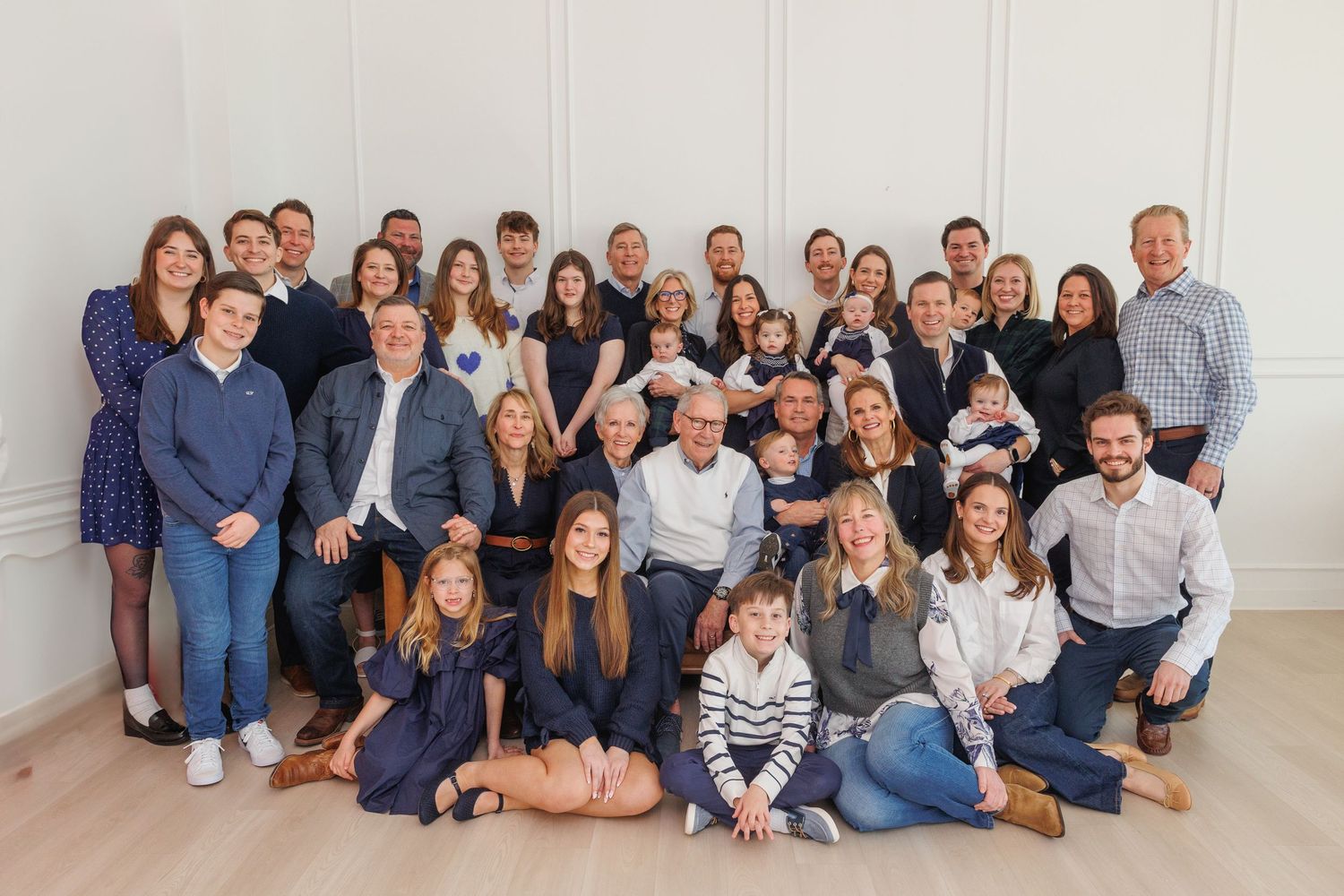 Large family group wearing coordinated blue and white outfits poses together for professional photos.