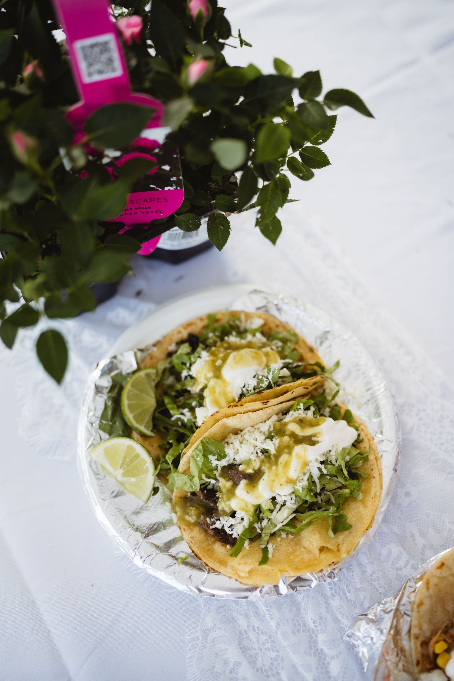 Fresh tacos arranged on white paper with garnishes including cilantro, lime, and cotija cheese.