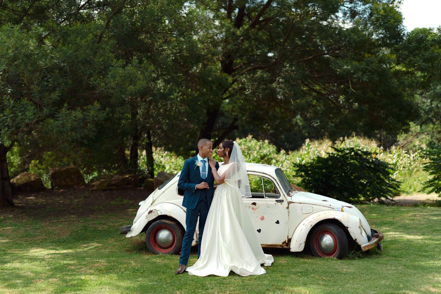 A sequence of romantic wedding photos taken outdoors in a lush garden setting with a classic white vintage car.