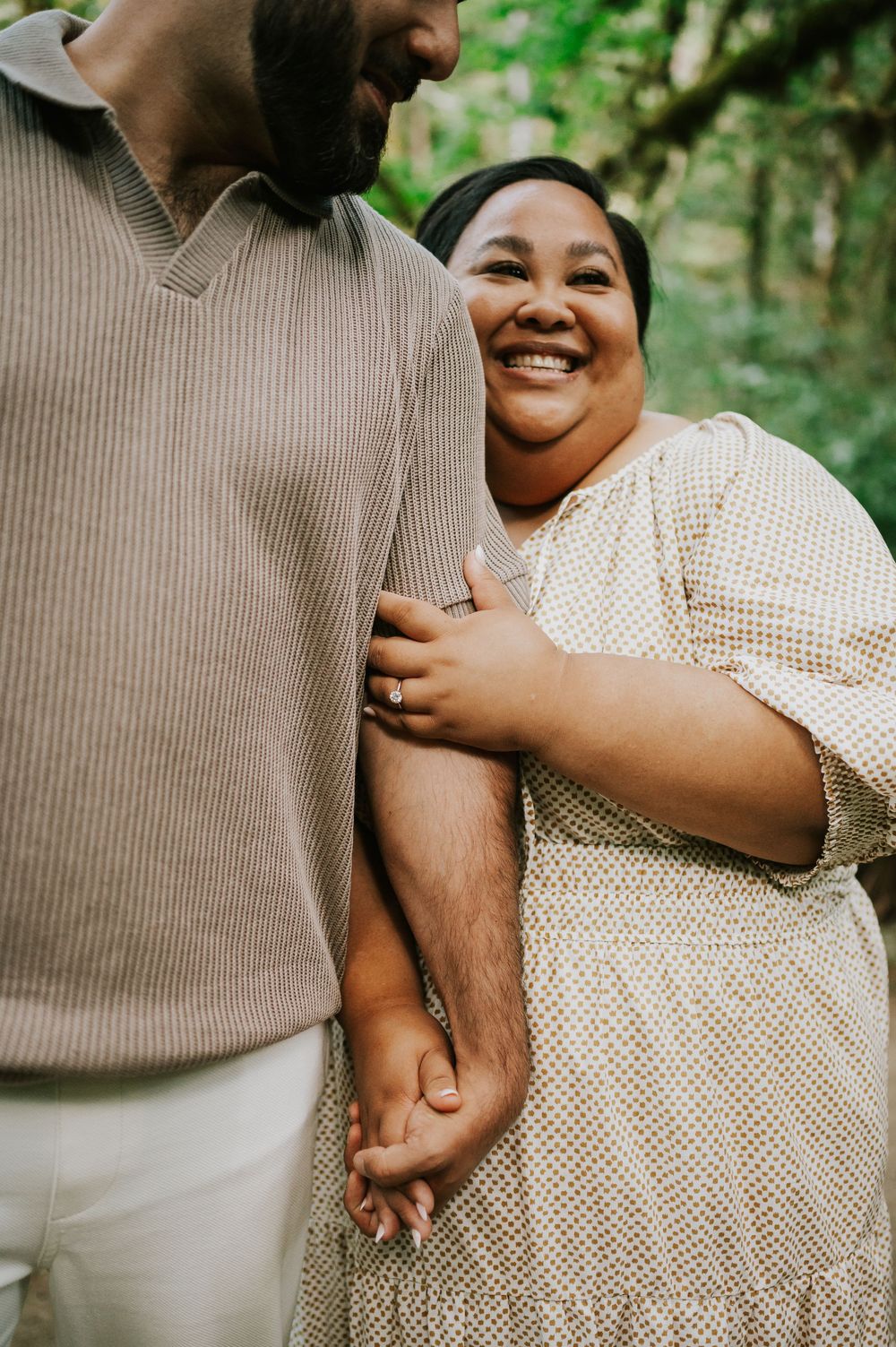 Photo of engaged couple holding arms and smiling with joy in Cathedral Groves, MacMillan Park. Vancouver Island adventure photographer