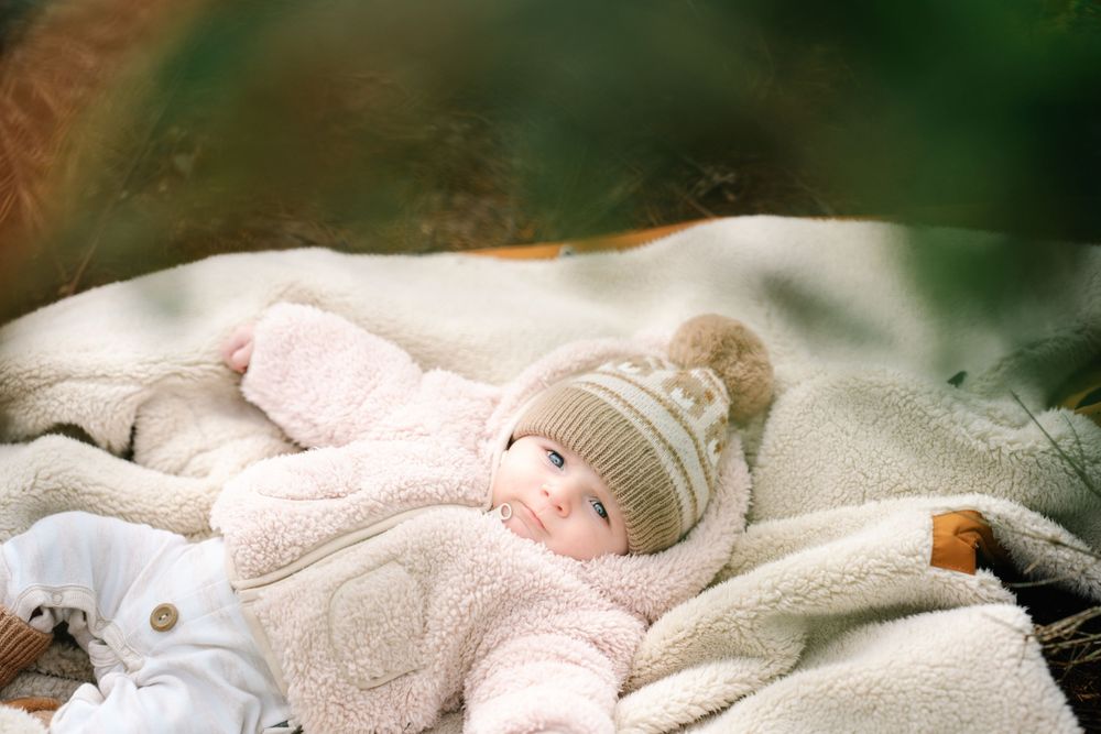 A row of adorable sleeping piglets nestled together in soft pink bedding material.