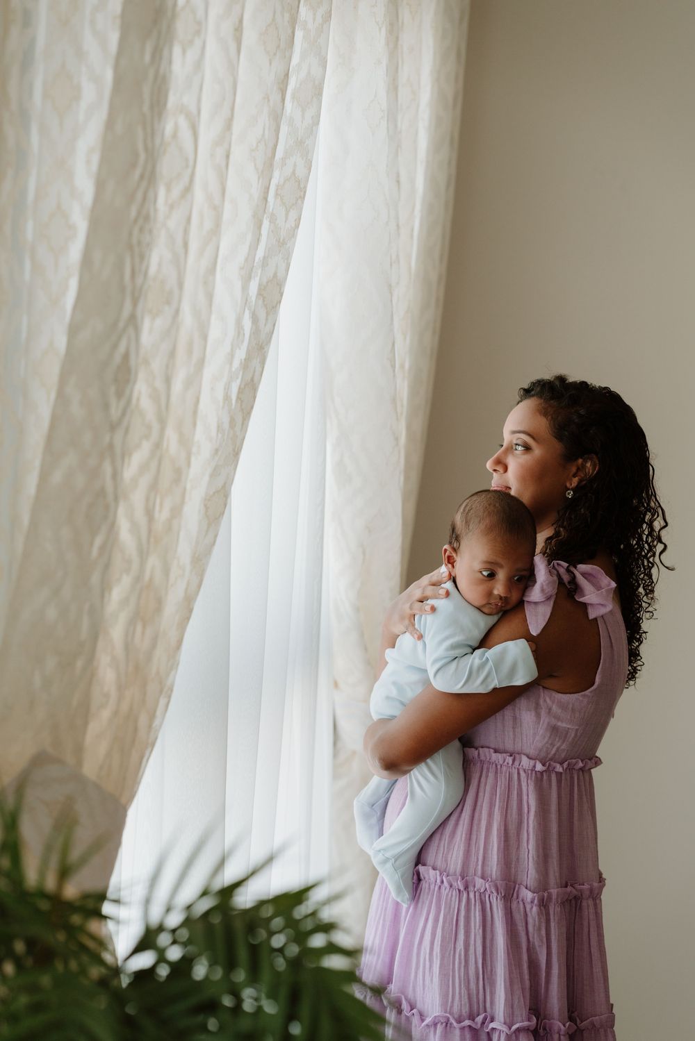 A peaceful portrait by sheer curtains of an embrace in soft natural lighting.