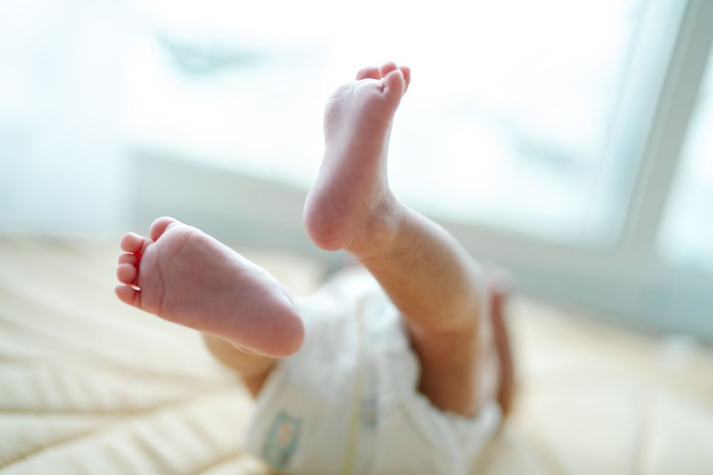 Close-up of tiny baby feet against a soft white background with natural window lighting.