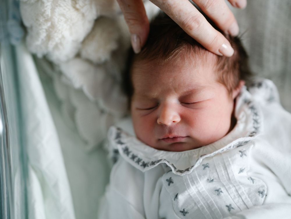 Close-up of a peaceful sleeping newborn in white lace trimmed clothing.