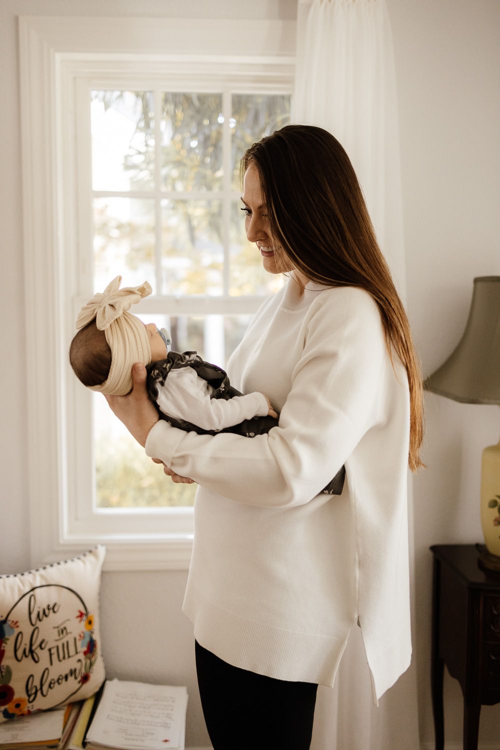 Mom holds her baby in front of a window