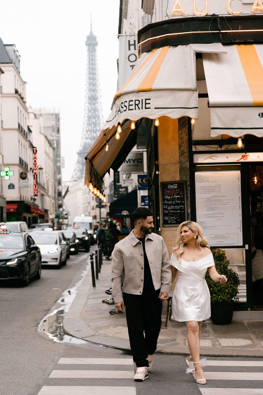 A romantic couple walks through charming Paris streets with the iconic Eiffel Tower visible in the background.