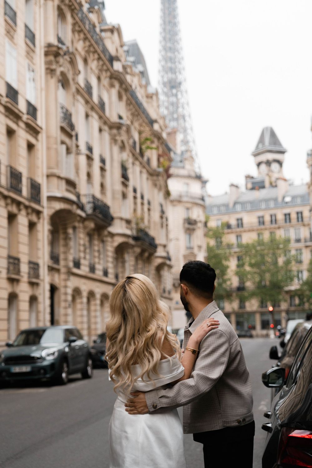 Romantic couple sharing intimate moments on a charming Parisian street with the Eiffel Tower visible in the background.
