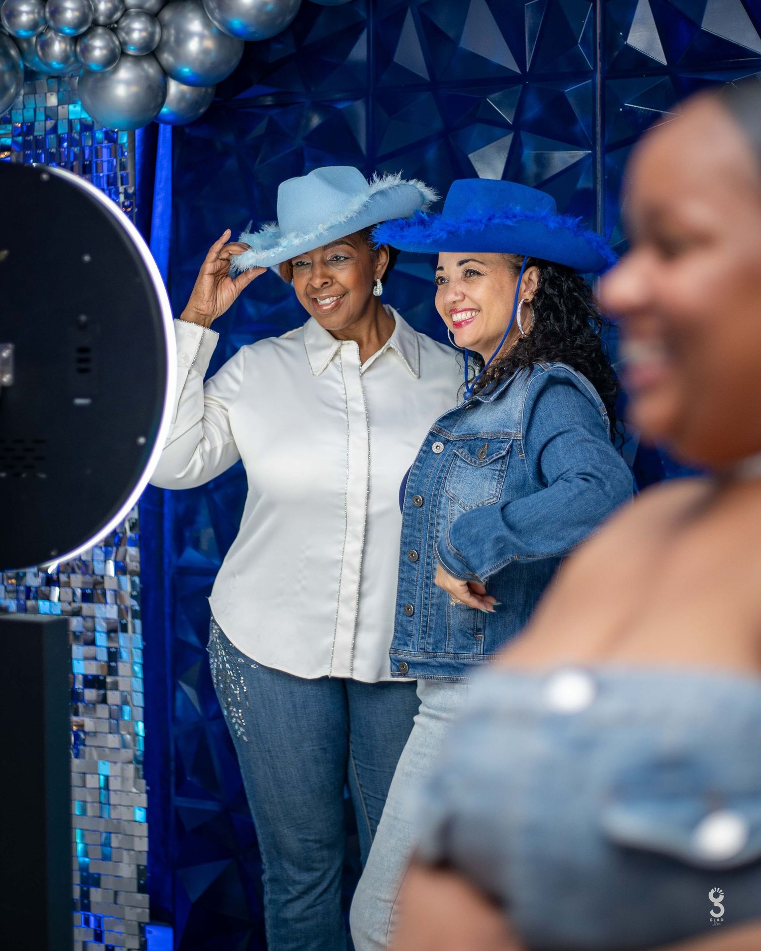 A couple shares an embrace and joyful laughter during what appears to be a special occasion with decorative lights in background.