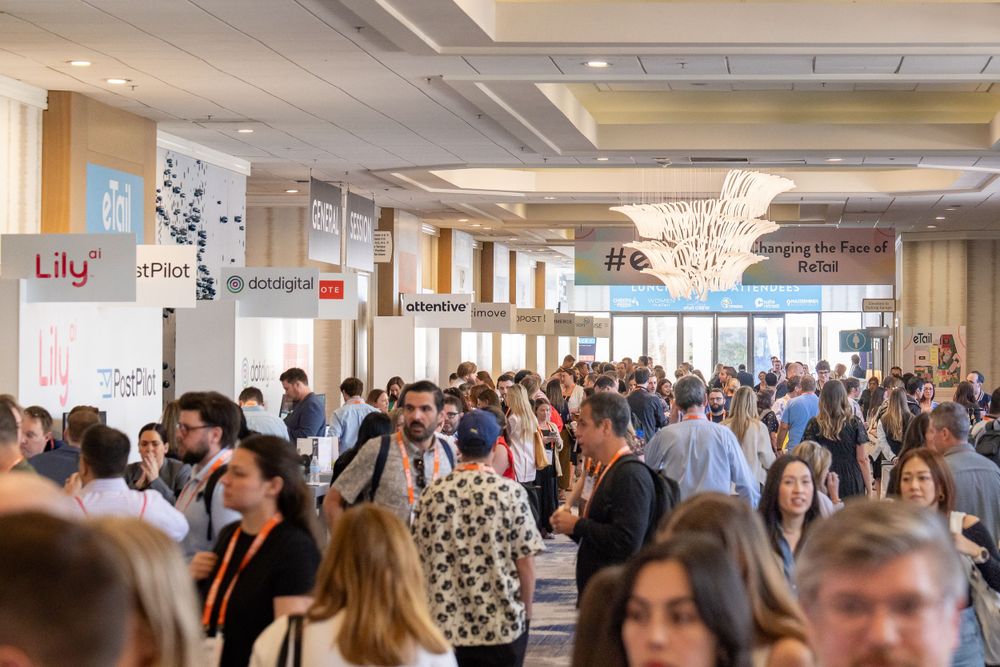 Crowded conference hallway with attendees networking under decorative lighting.