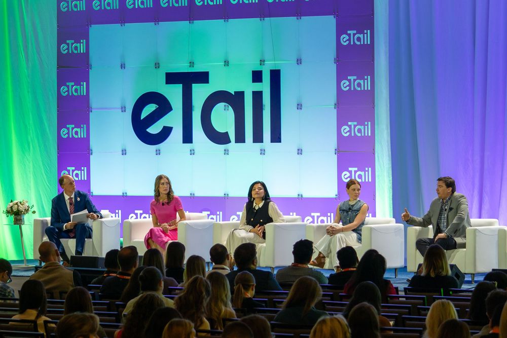 Business conference panel discussion at eTail event with purple stage lighting.
