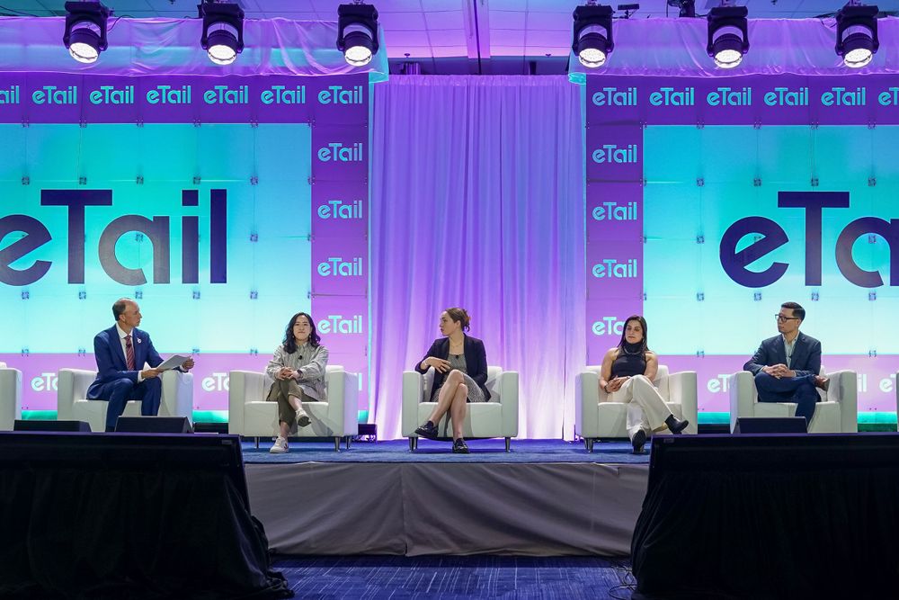 Panel discussion at eTail conference with speakers seated on stage with purple lighting.