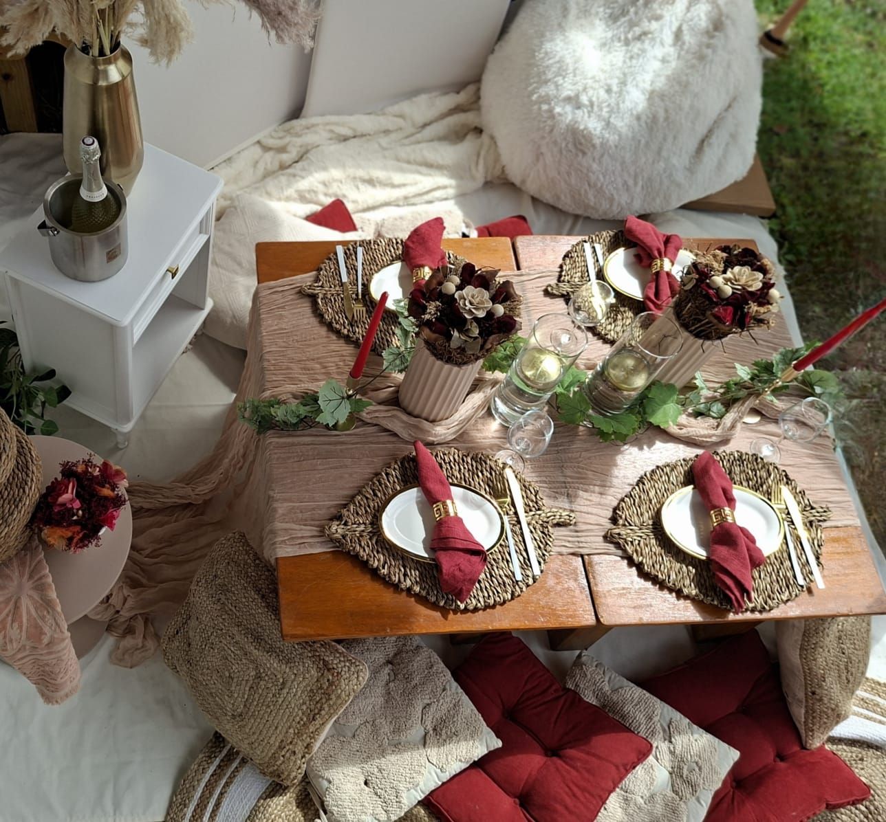 Elegant boho Valentine's Day table setting with red accents, candles, and greenery.