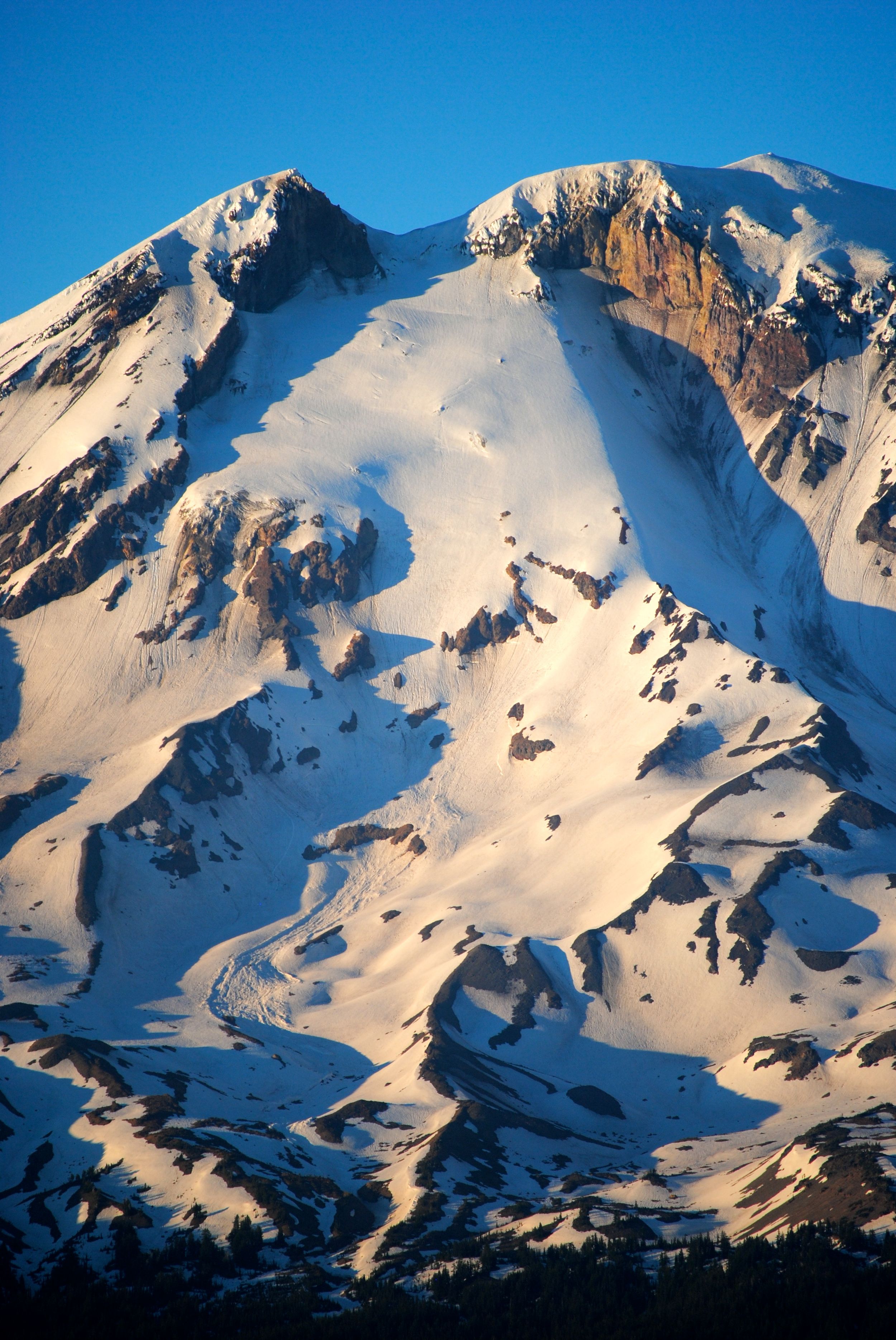 Snow-covered mountain peak with dramatic rock faces and glacial formations.