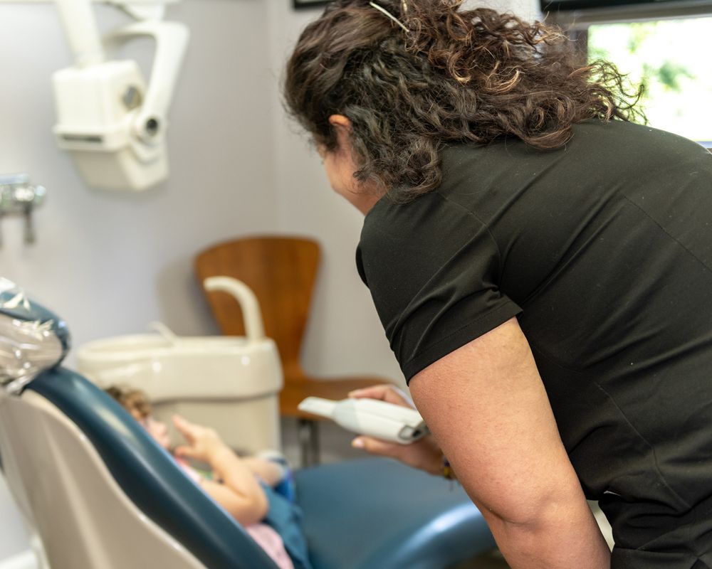 Healthcare provider working with dental equipment in treatment room.