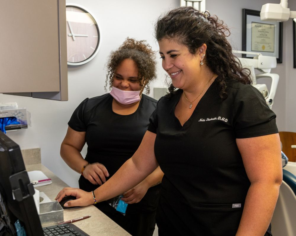 Medical staff members collaborating at computer workstation in clinical setting.