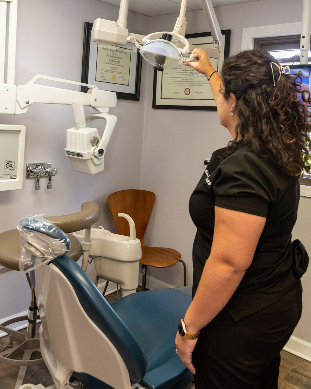 Healthcare worker adjusting dental equipment in modern examination room.