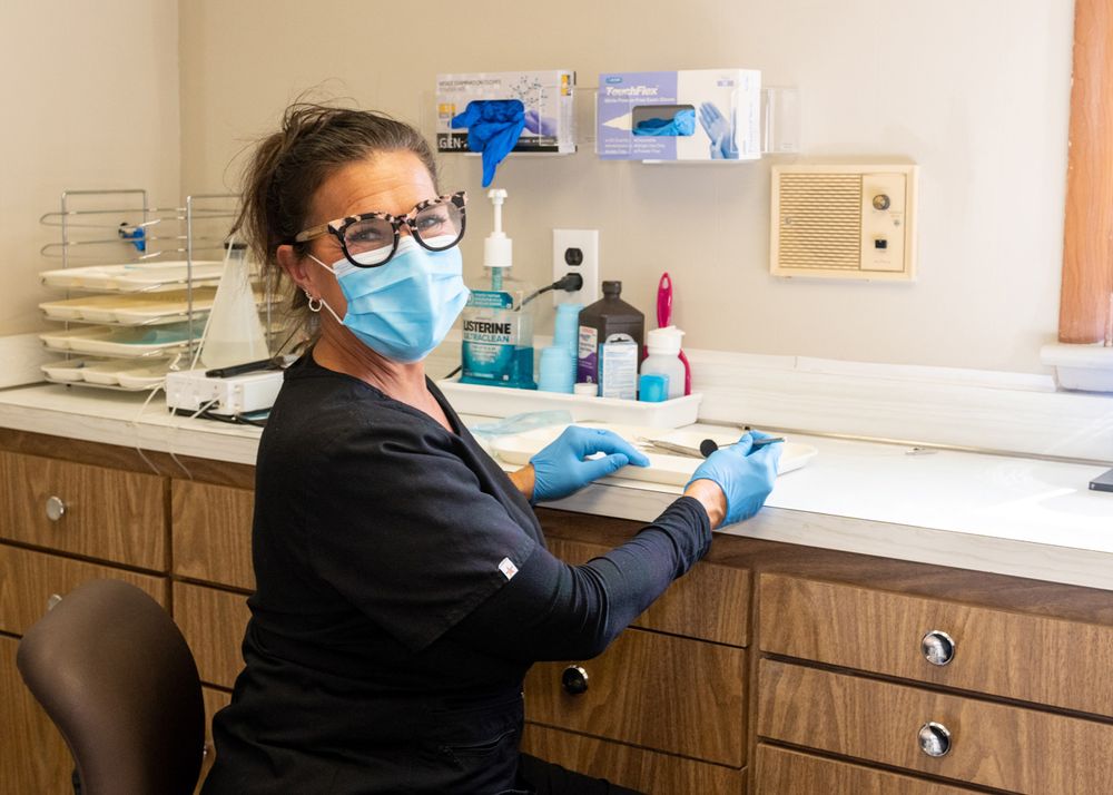 Medical staff member in protective gear working at clinical workspace with supplies.