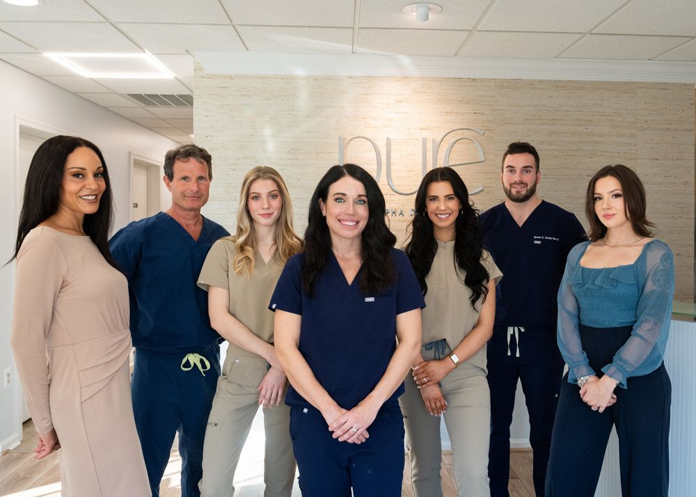 Medical office team members posing together in front of branded wall.