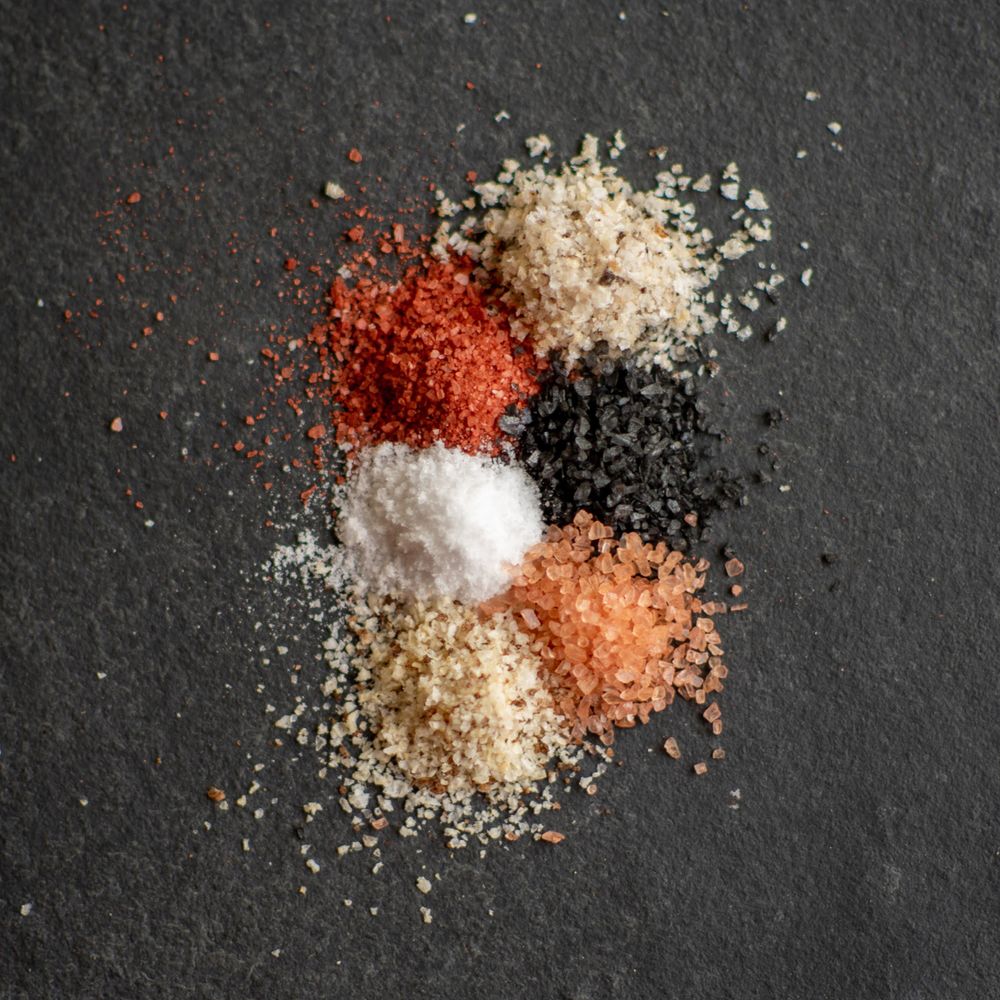 Various colorful spices and seasonings arranged on black slate surface.