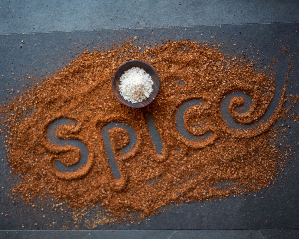 The word 'spice' written in brown seasoning with a small bowl of salt.