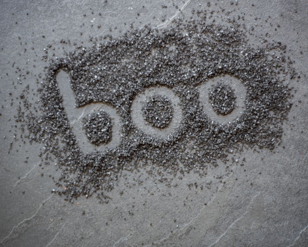 The word 'boo' written in black pepper on a gray surface.