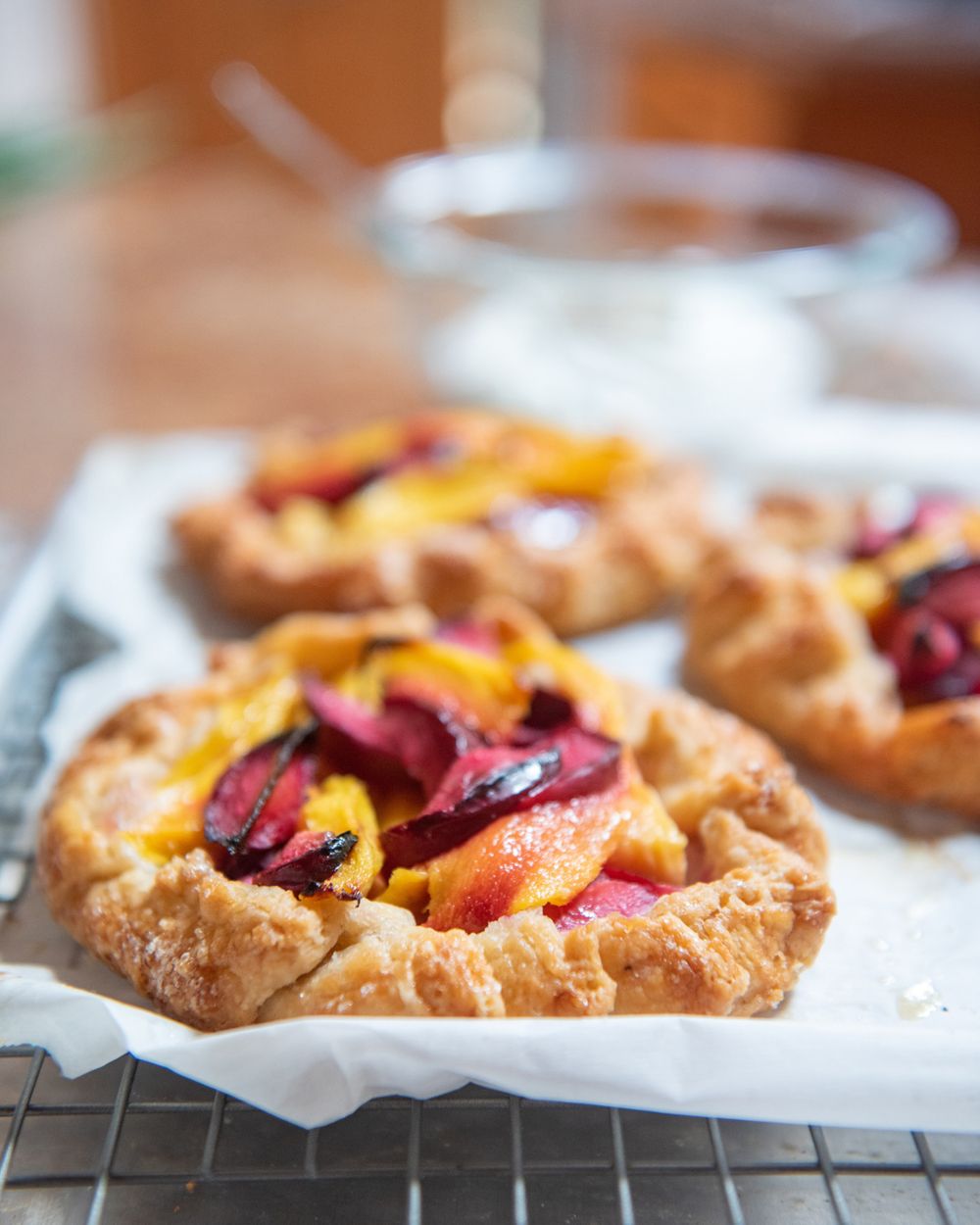 Rustic fruit galettes with peaches and berries cooling on parchment paper.