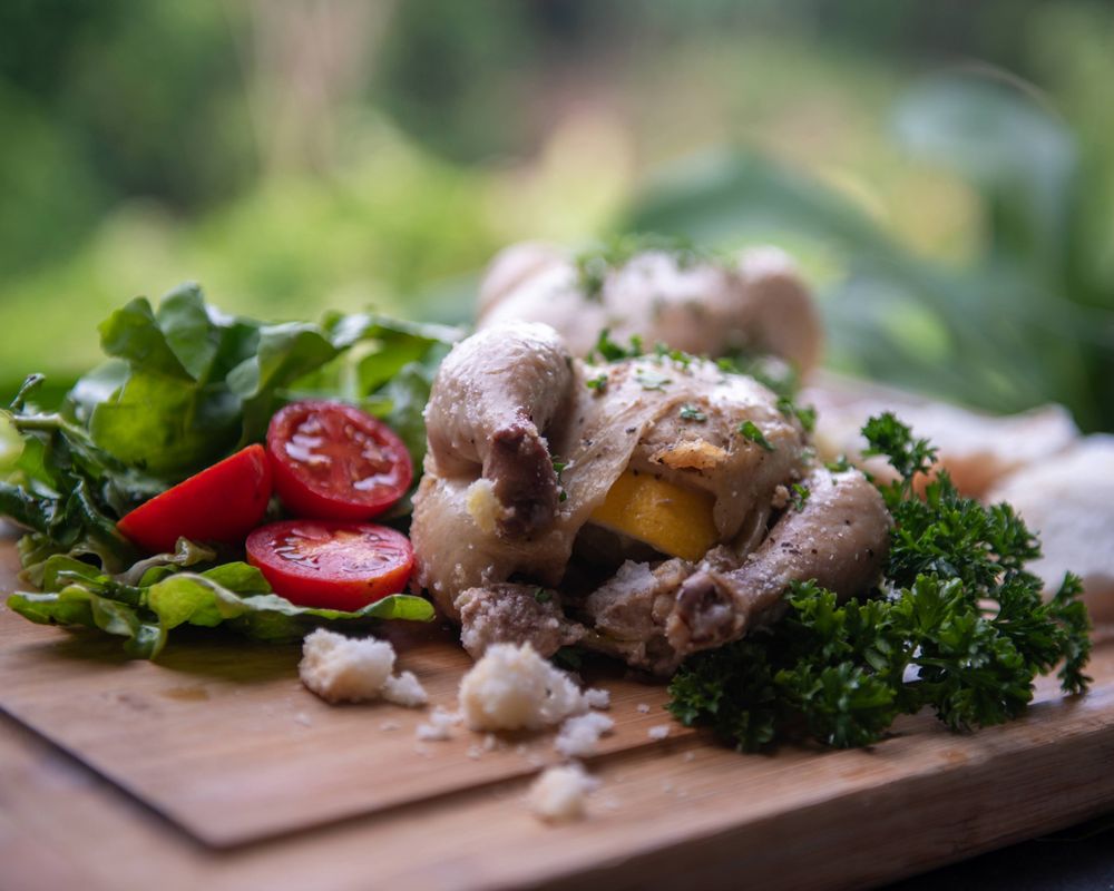 Grilled quail with fresh herbs, cherry tomatoes and greens on wooden board.