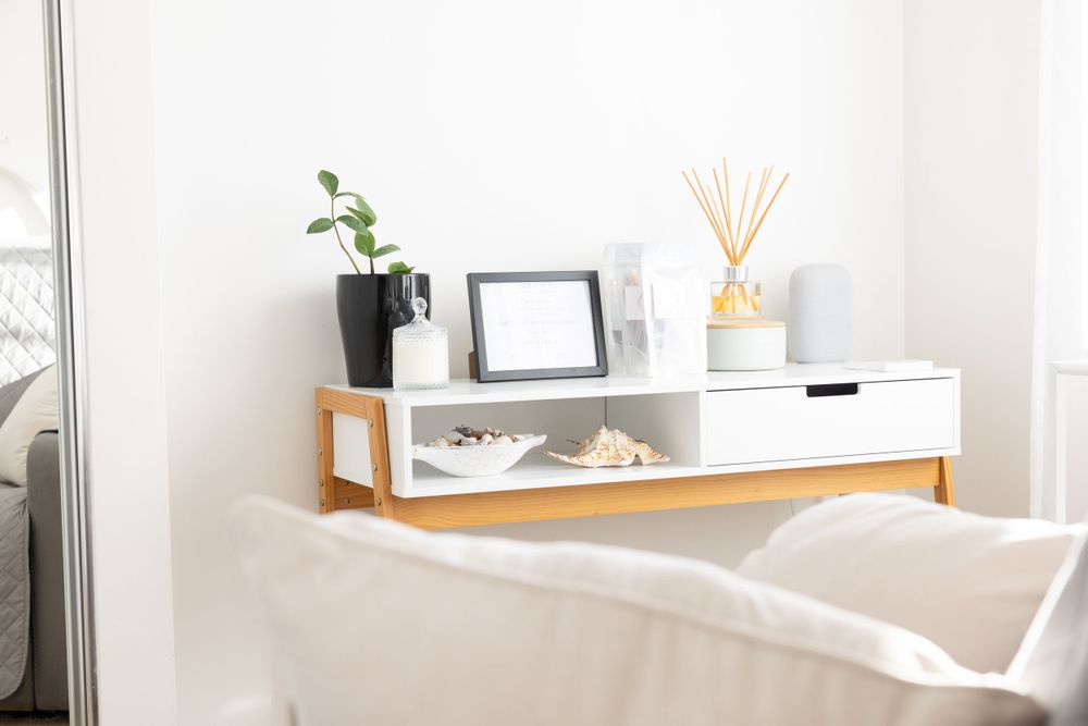Modern shelf unit with plants, frame and decorative items against white wall.