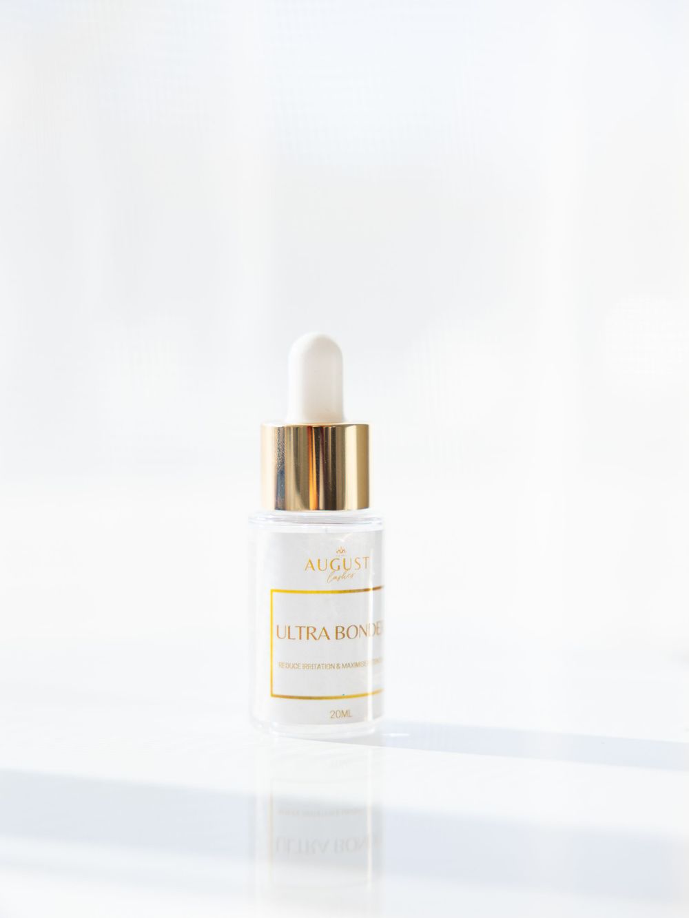 White dropper bottle with gold accents against white background.