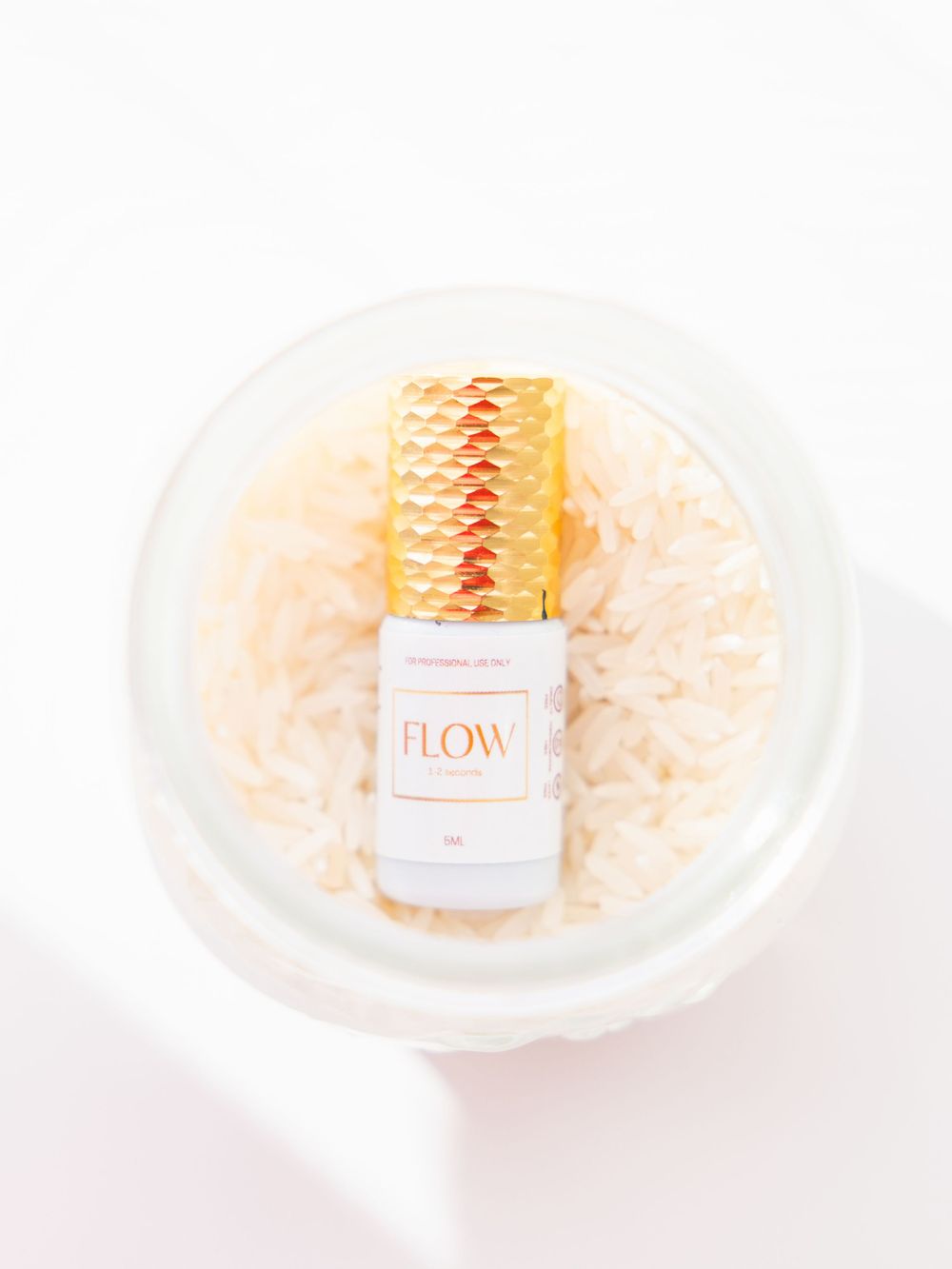 Glass bottle labeled 'Flow' displayed on white shredded paper in clear container.