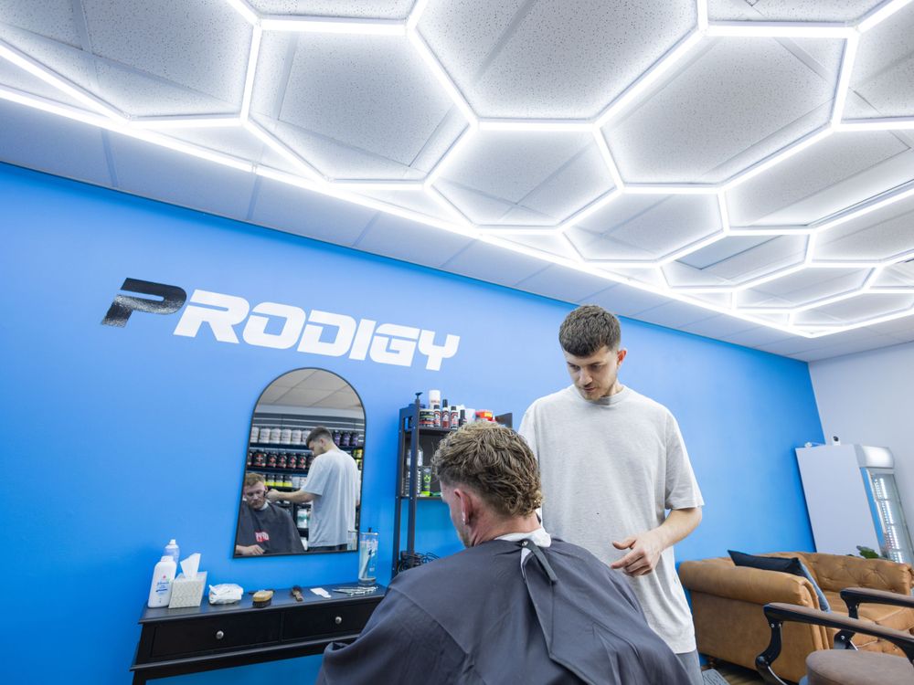 Modern barbershop interior featuring hexagonal ceiling lights and bright blue accent wall.