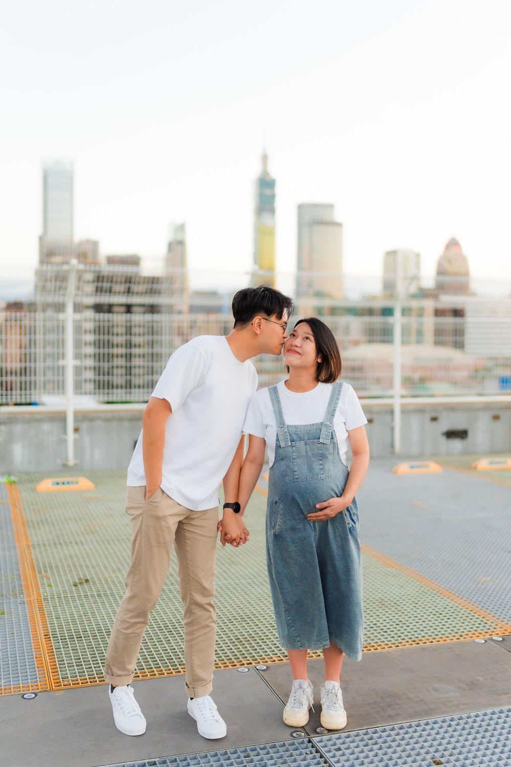 Romantic moment captured on urban rooftop with dramatic city skyline at dusk.