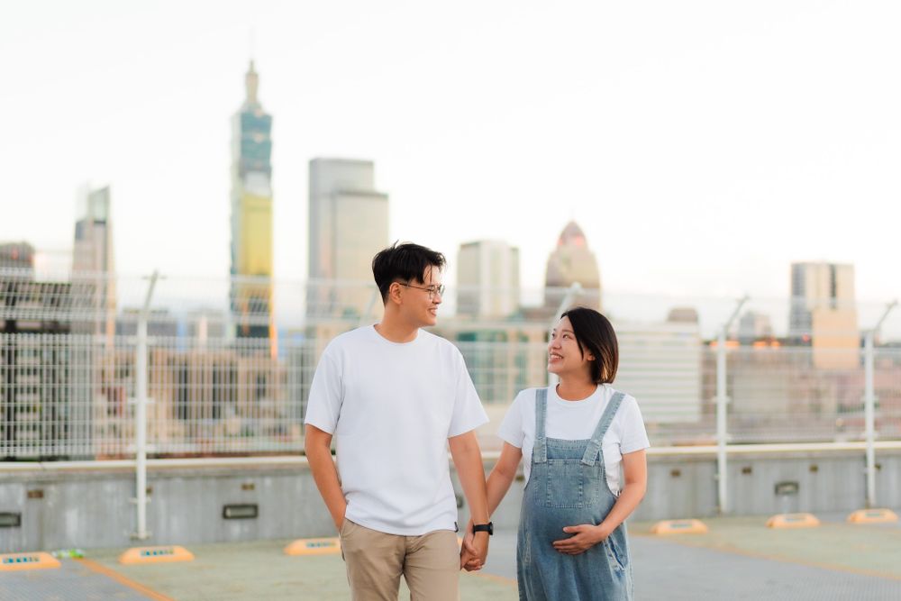 Couple walking hand in hand on rooftop with urban skyline in background.