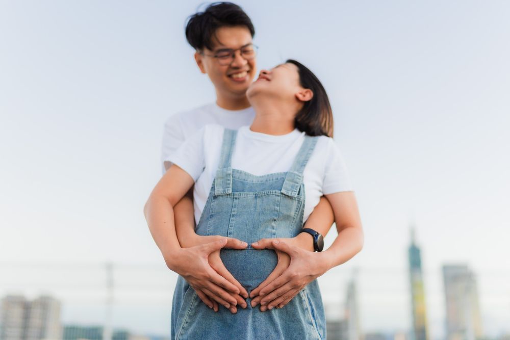Couple embracing on rooftop terrace with city buildings in background.