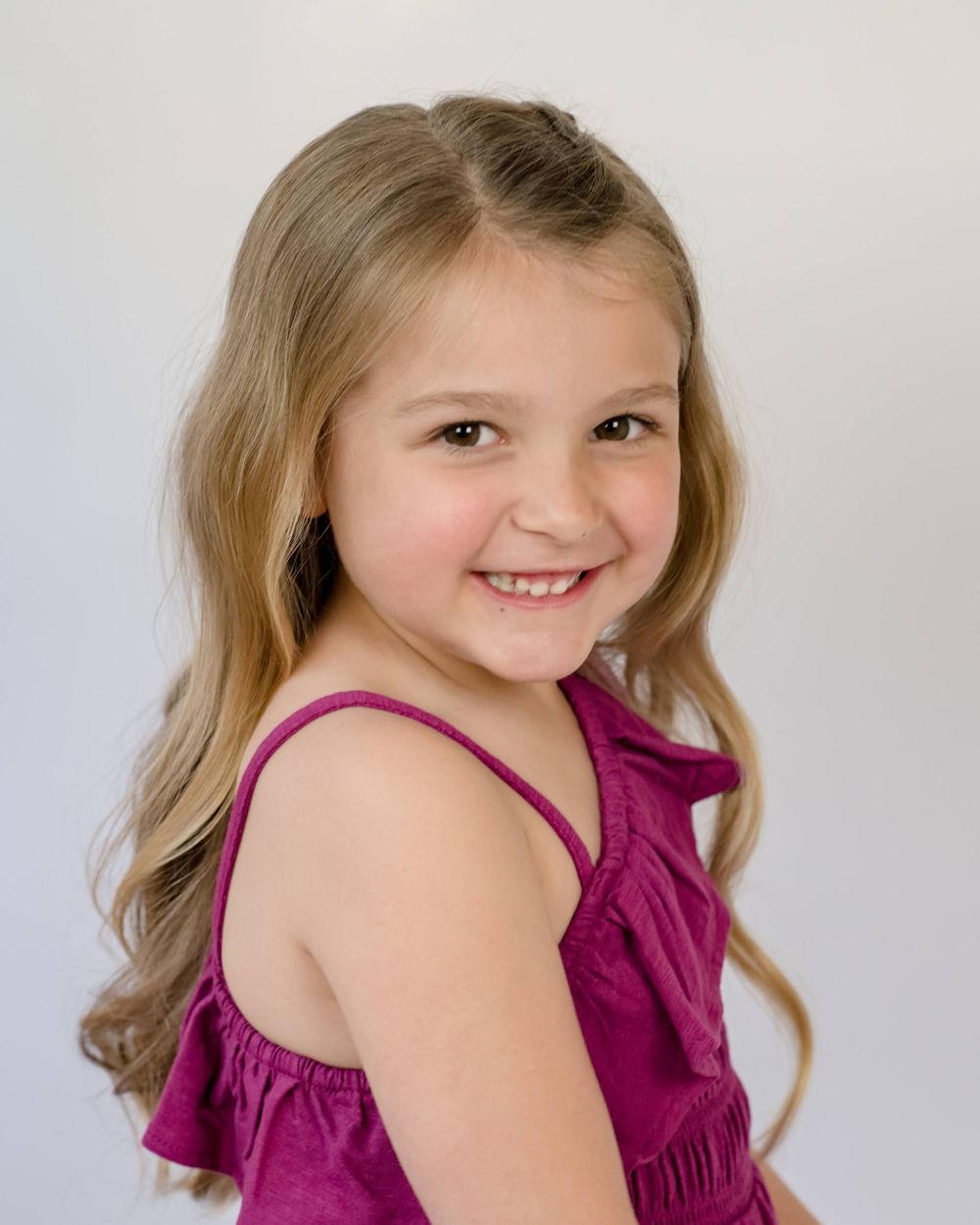 Studio portrait in magenta dress against light background.