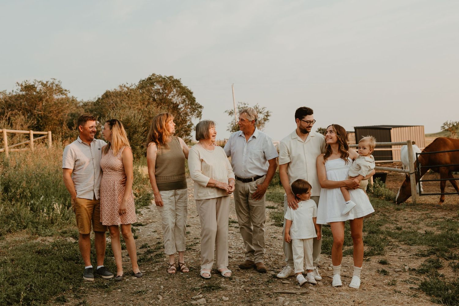Family members dressed in white and neutral colors pose together on a rustic path at sunset.